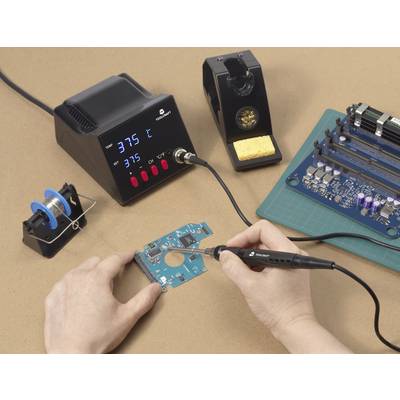 Ein Mensch arbeitet mit einem Lötkolben an einer blauen Leiterplatte, umgeben von einer Lötestation, Lötzinn und elektronischen Bauteilen.