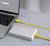 Ein Laptop mit grauem Bildschirm, verbunden mit einer externen Festplatte. Das gelbe Kabel hat Markierungen wie ein Maßband.