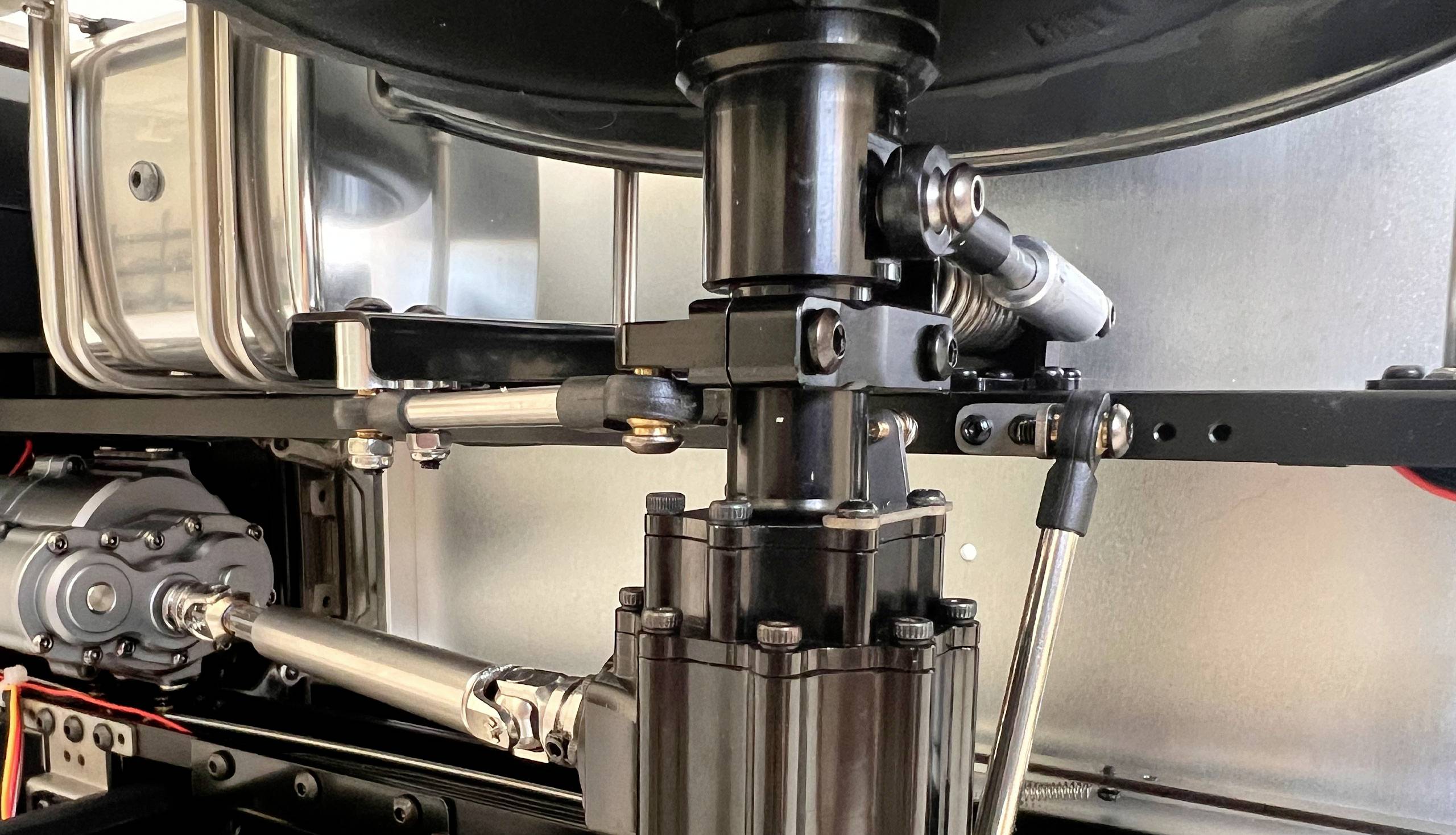 Maschinezoom zeigt Metallkomponenten, darunter ein Hydraulikzylinder, Hebel und Rohre. Fokus liegt auf deren mechanischer Verbindung.