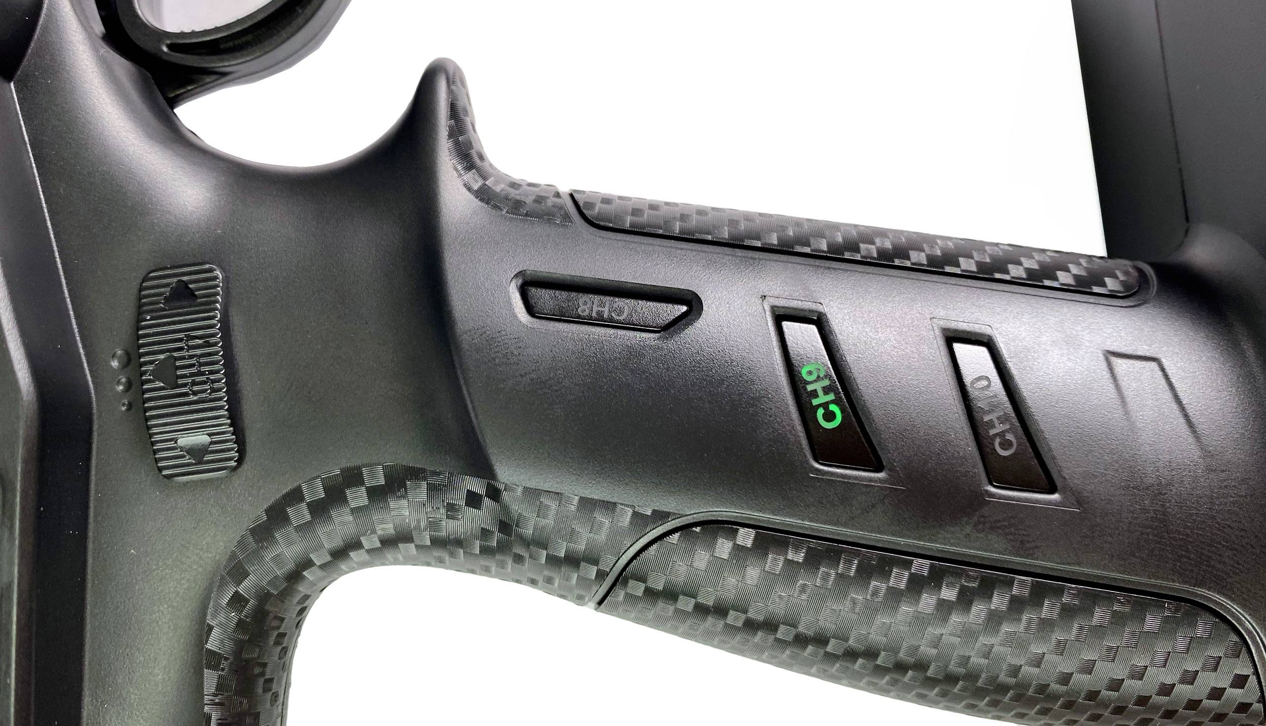 Nahaufnahme eines schwarzen Fernsteuerungsgriffs mit drei Tasten und Kanalbezeichnungen 'CH1', 'CH2', 'CH3'. Oberfläche wirkt texturiert.