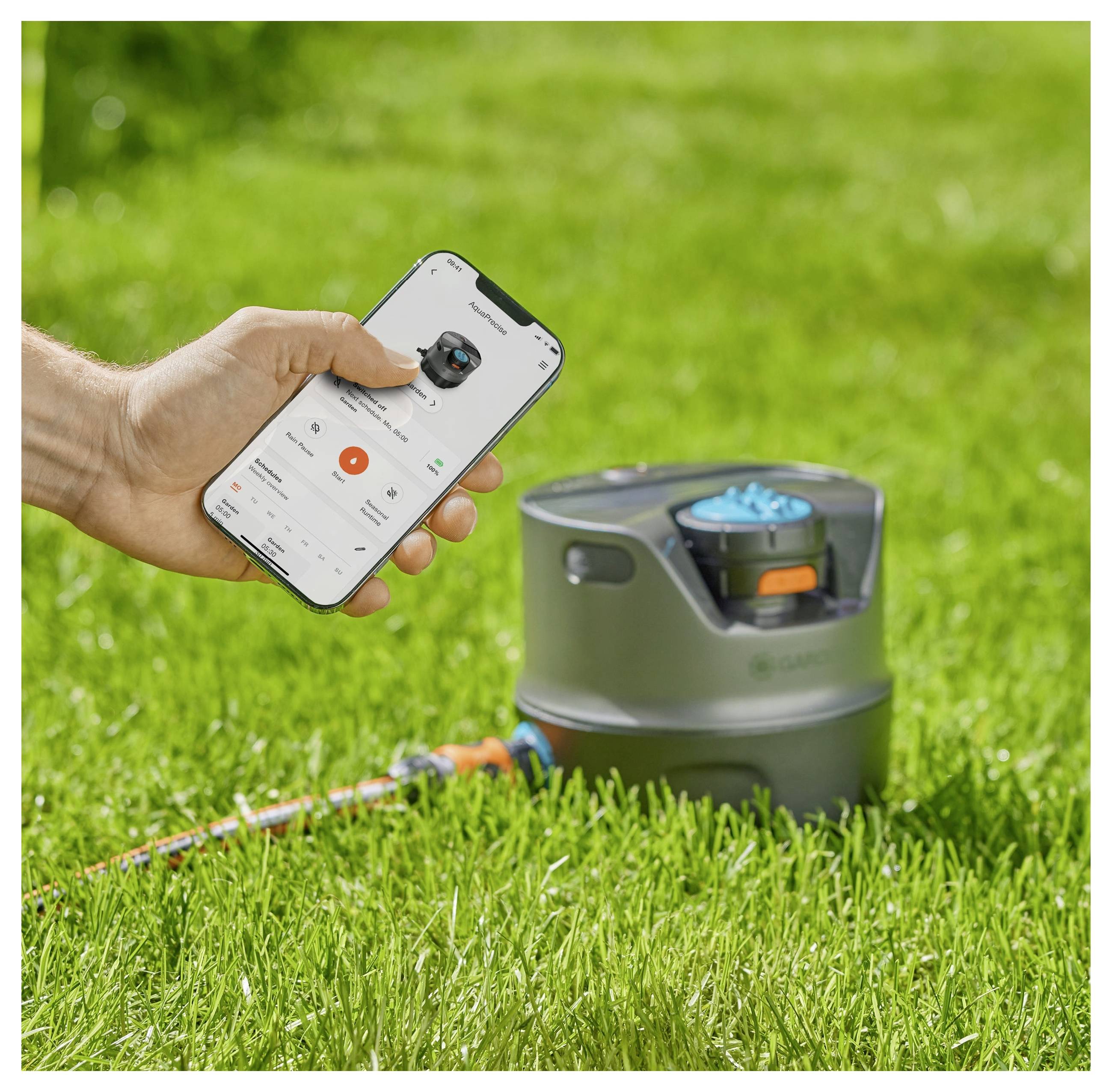 Eine Person nutzt eine Smartphone-App, um ein Sprinklersystem auf einem grünen Rasen zu steuern.