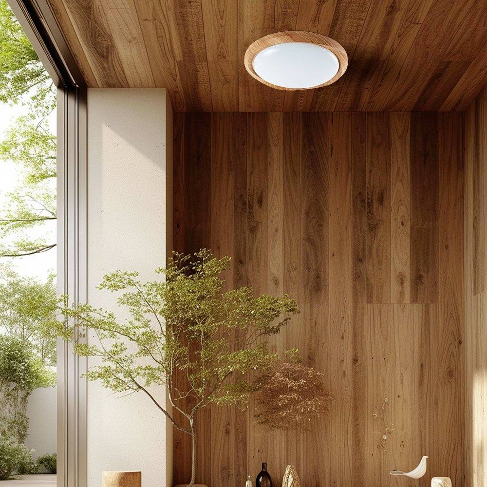 Offener Raum mit Holzwänden und -decke; Fenster zeigt grünen Baum draußen. Helle, warme Beleuchtung vom Deckenlicht. Minimalistische Dekoration.