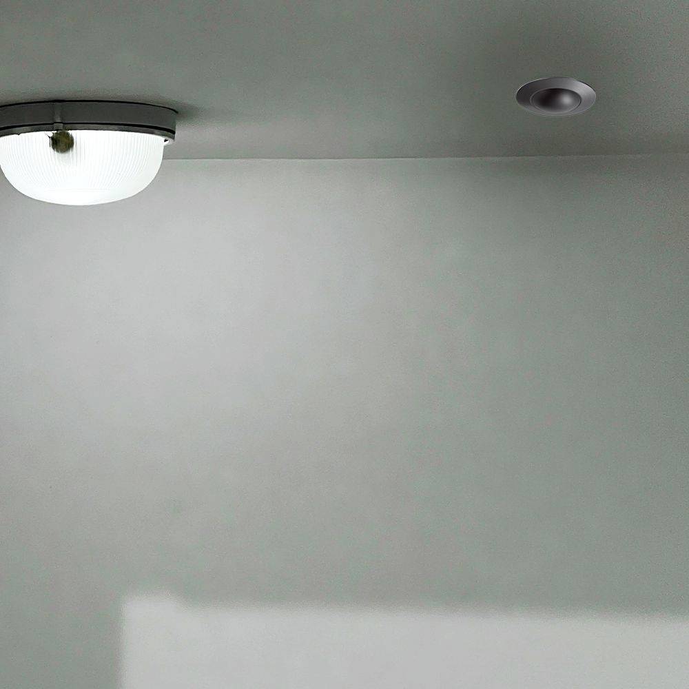 Deckenleuchte und Rauchmelder an einer weißen, schlichten Decke montiert.