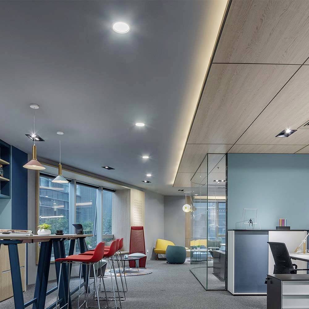 Moderne Büroetage mit farbenfrohen Möbeln, Lounge-Bereich und großen Fenstern. Helle Beleuchtung schafft eine einladende Atmosphäre.