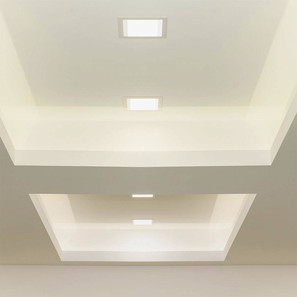 Deckenbeleuchtung mit drei quadratischen Einbauleuchten in einem modernen, minimalistisch gestalteten Raum.
