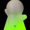 Eine weiße, spukhafte Figur mit grün leuchtendem Sockel, auf schwarzem Hintergrund. Unten ist ein blaues Logo mit einem 'M' sichtbar.