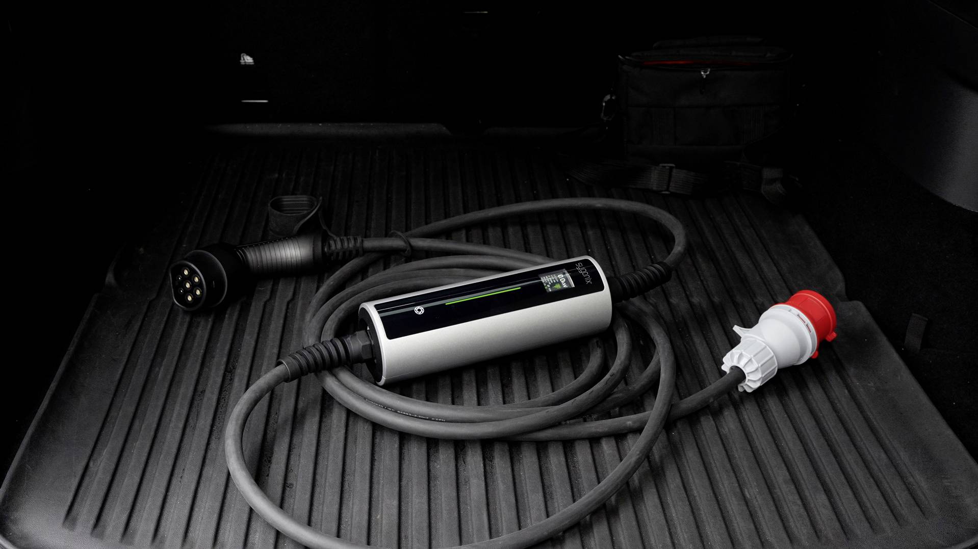 Ein Ladekabel für Elektrofahrzeuge liegt auf einer Kofferraummatte im Auto, mit einem Typ-2-Stecker und einem CEE-Stecker.