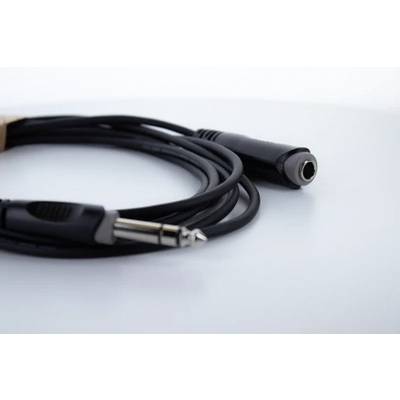 Ein schwarzes Audiokabel mit einem 6,35 mm Klinkenstecker und einer Buchse liegt auf einem weißen Hintergrund.