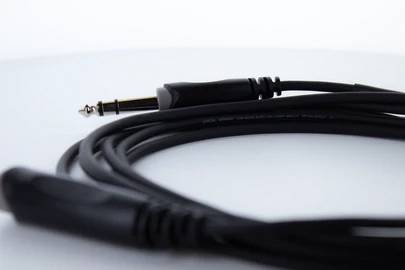 Ein langes, schwarzes Audiokabel mit einem 6,3 mm Klinkenstecker liegt aufgerollt auf einem Tisch.