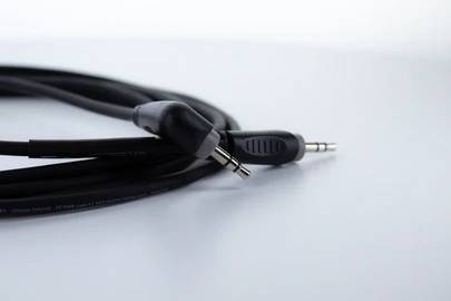 Ein schwarzes Audiokabel mit zwei 3,5-mm-Steckern liegt auf einem hellen Untergrund.