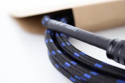 Ein schwarzes, blau gestreiftes Kabel ragt aus einem offenen braunen Karton hervor, Teil eines technischen Geräts oder Werkzeugs.