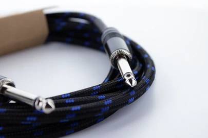 Schwarzes Audiokabel mit blauem Muster und zwei Klinkensteckern, aufgerollt auf weißem Hintergrund.