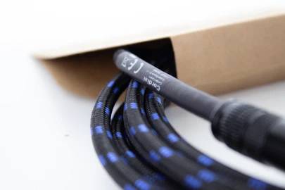 Ein schwarzes, geflochtenes Kabel mit blauen Akzenten ragt aus einem braunen Karton heraus.