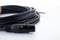 Ein langes, schwarzes Audiokabel mit einem XLR-Stecker und einem Klinkenstecker liegt locker aufgerollt auf einer weißen Oberfläche.