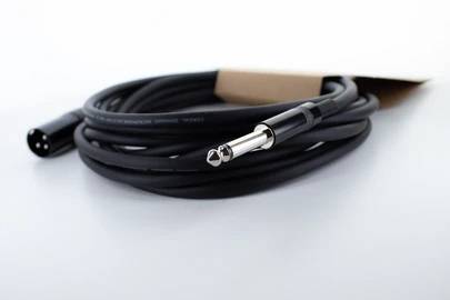 Ein langes, schwarzes Audiokabel mit einem XLR-Anschluss an einem Ende und einem 6,35 mm Klinkenstecker am anderen liegt aufgerollt auf einer weißen Oberfläche.