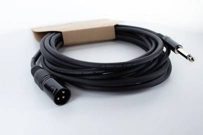 Ein schwarzes Audio-Kabel mit einem XLR-Stecker auf der einen Seite und einem 6,3 mm Klinkenstecker auf der anderen, liegt aufgerollt.