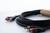 Ein langes Audiokabel mit zwei RCA-Steckern, einem roten und einem weißen, liegt aufgerollt auf einem weiß-grauen Hintergrund.