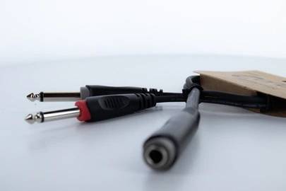Nahaufnahme von Audio-Adapterkabeln mit verschiedenen Steckertypen, die aus einem Pappkarton ragen, auf einer hellen Oberfläche.