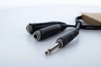 Zwei Metalladapter mit schwarzem Kabel verbunden liegen auf einer Oberfläche. Der Fokus liegt auf dem vorderen, silbernen Klinkenstecker.