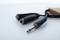 Zwei Metalladapter mit schwarzem Kabel verbunden liegen auf einer Oberfläche. Der Fokus liegt auf dem vorderen, silbernen Klinkenstecker.