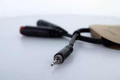 Ein schwarzes Audiokabel mit einem silbernen 3,5-mm-Klinkenstecker vorne und zwei roten und schwarzen RCA-Steckern hinten.