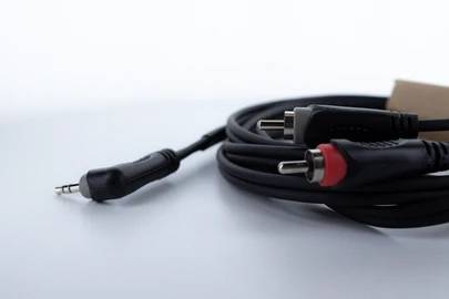 Ein Audiokabel mit einem 3,5-mm-Stecker und zwei Cinch-Steckern, einem roten und einem weißen, auf einem weißen Hintergrund.