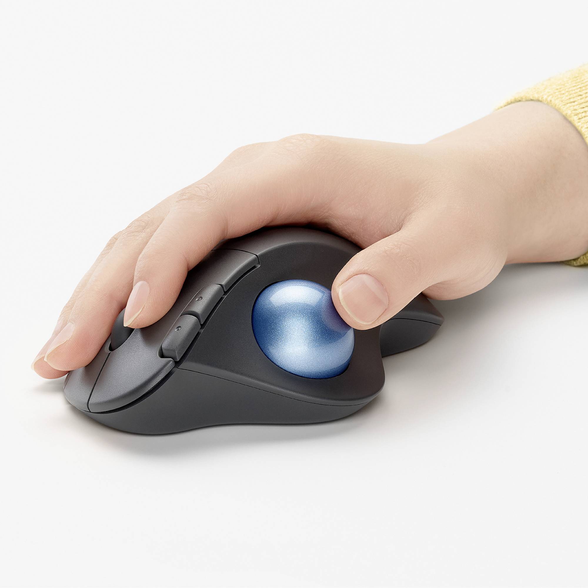 Eine Hand bedient eine ergonomische Trackball-Maus, die auf einem Tisch liegt. Die Maus hat einen blauen Trackball in der Mitte.