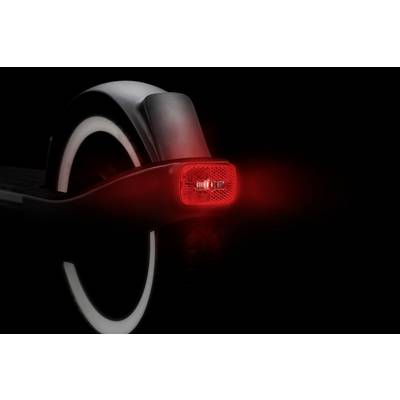 Ein elektrischer Roller von hinten, mit leuchtendem roten Rücklicht und reflektierender Oberfläche, auf schwarzem Hintergrund.