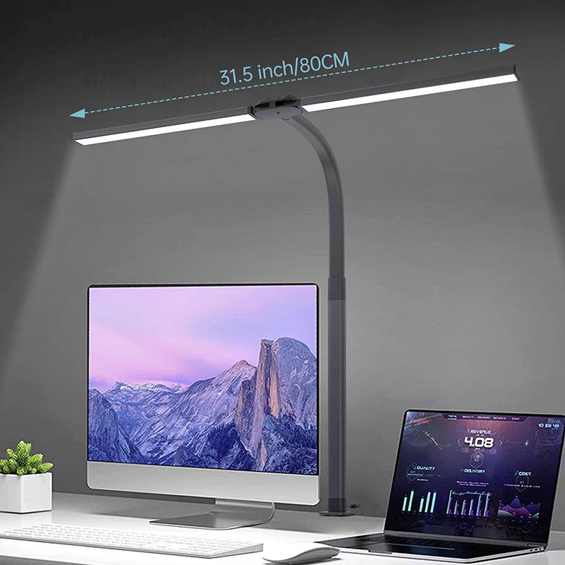 Ein moderner Arbeitsplatz mit einem großen Computermonitor und einem Laptop. Eine LED-Lampe leuchtet den Bereich gleichmäßig aus.