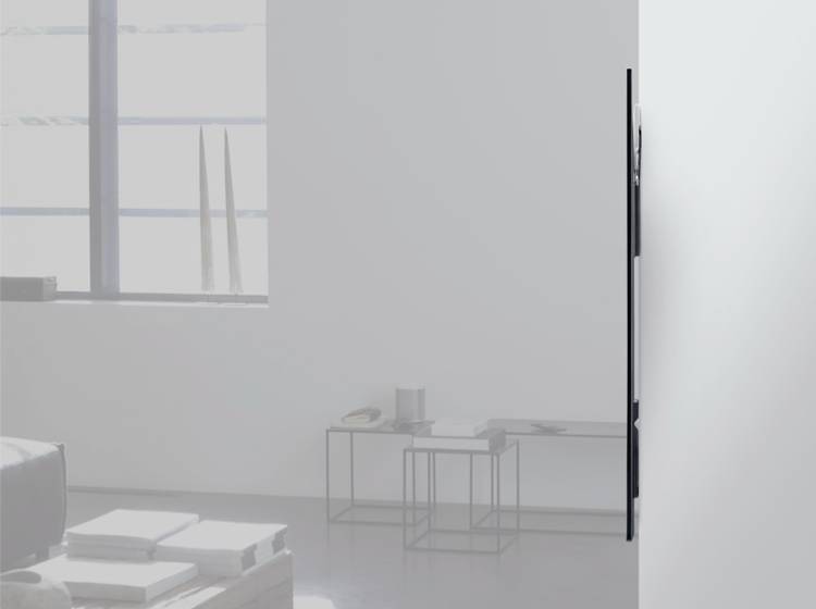 Ein minimalistisches Wohnzimmer mit einem an der Wand montierten Flachbildfernseher, modernen Möbeln und großen Fenstern im Hintergrund.