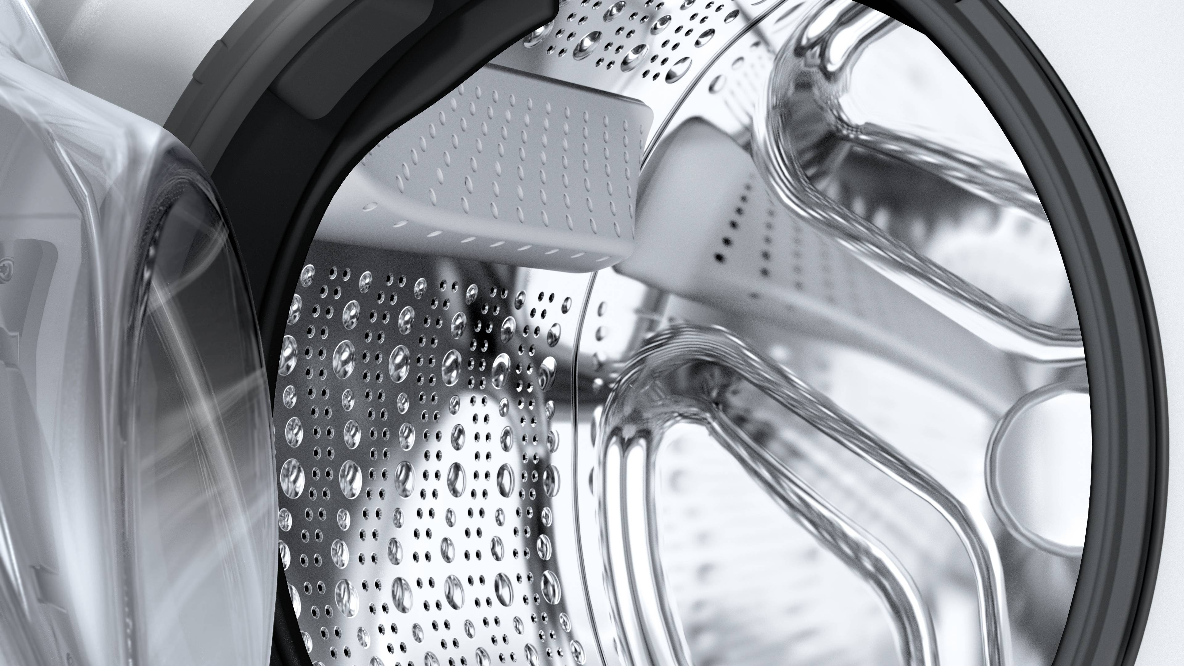 Blick in die Trommel einer Waschmaschine mit Wassertröpfchen. Die Oberfläche aus Edelstahl ist glänzend und strukturiert.
