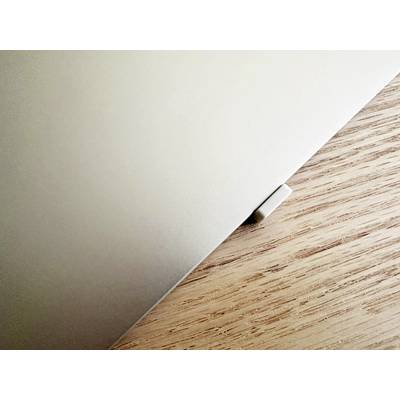 Ein Laptop, teilweise geschlossen, liegt auf einem Holztisch. Ein Teil der Ecke ragt hervor, ohne weitere sichtbare Objekte.
