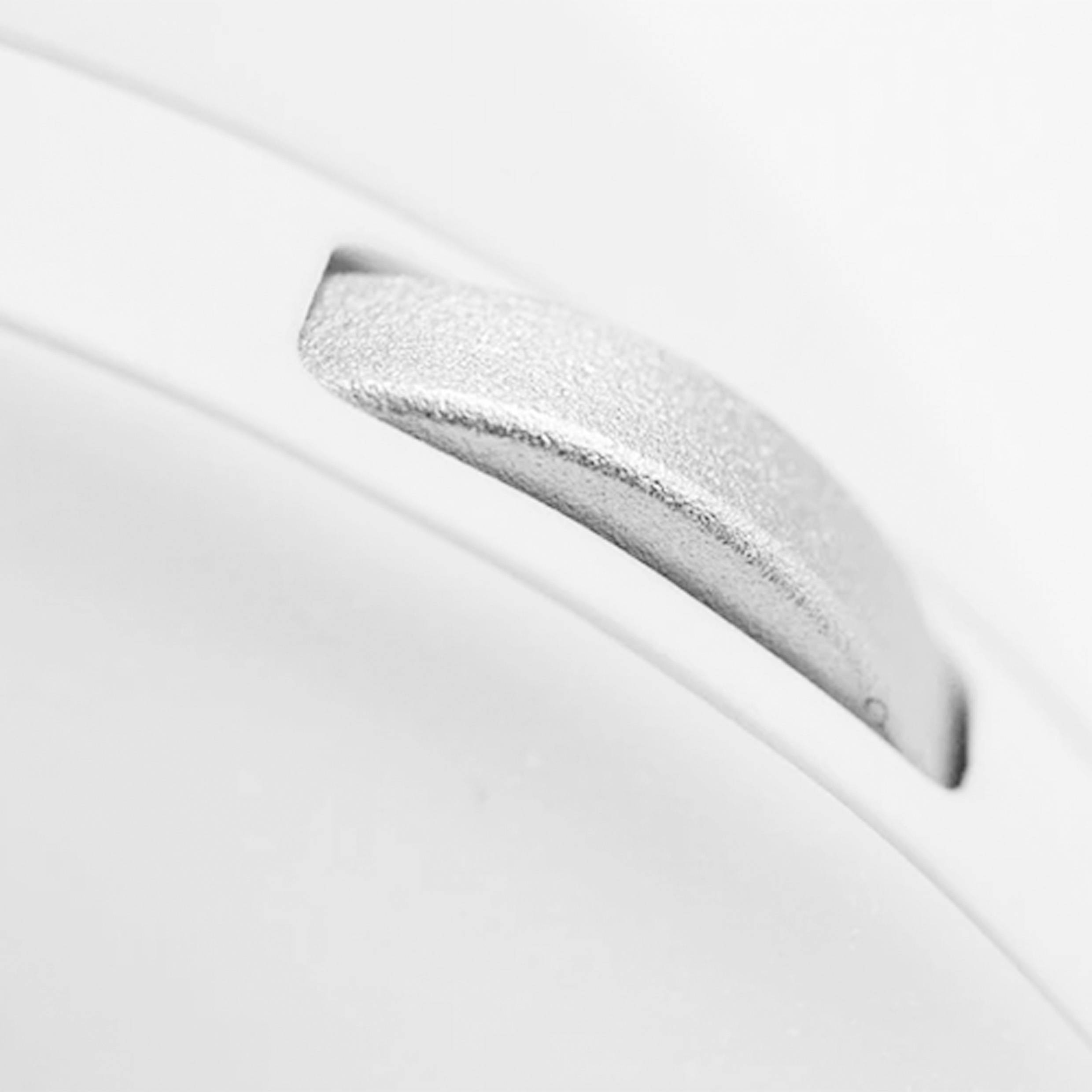 Ein silberner Metallhebel ragt aus einer weißen Oberfläche heraus.