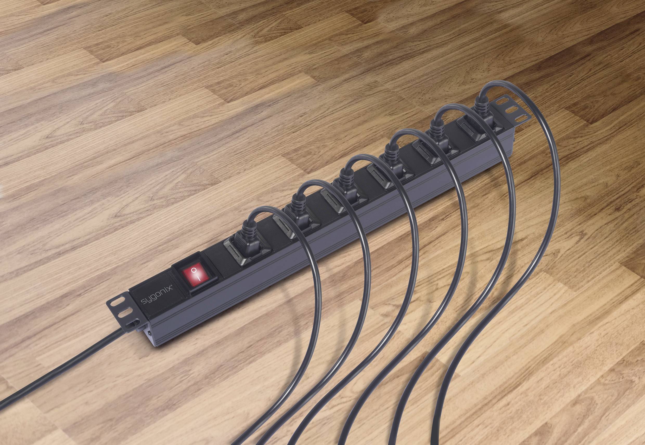 Eine schaltergesteuerte Steckdosenleiste mit sechs angeschlossenen schwarzen Kabeln liegt auf einem Holzfußboden.