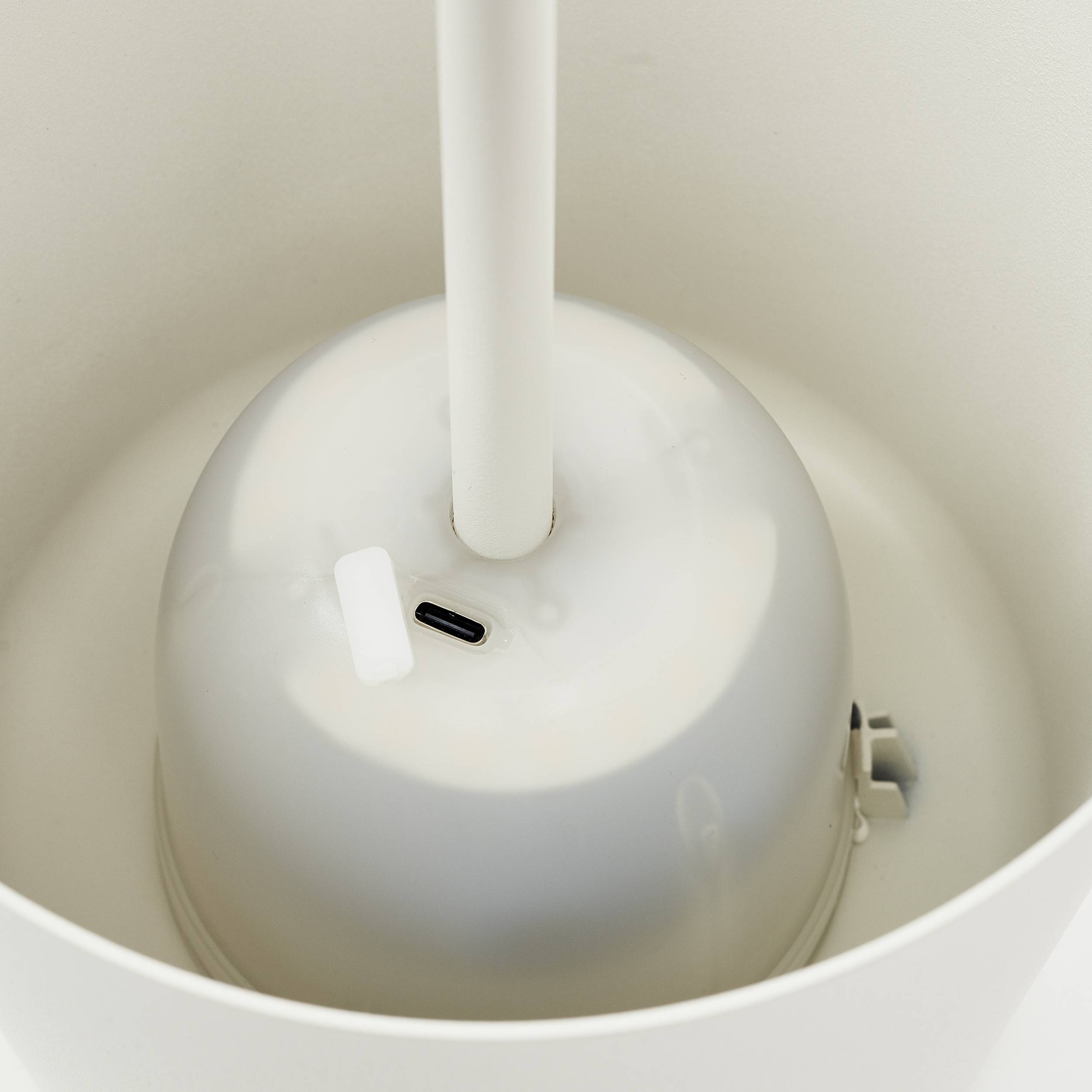 Eine weiße Lampe mit USB-C-Anschluss oben. Sie steht in einem hellen Raum.