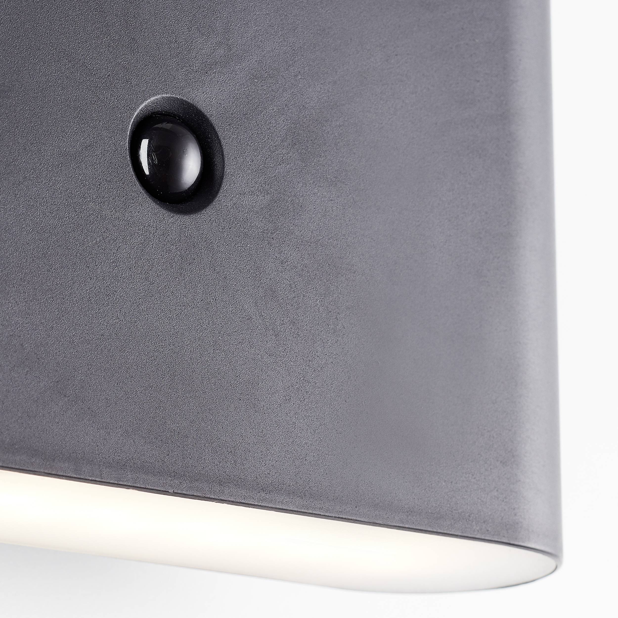Wandleuchte aus mattem Metall mit einem zentralen, kleinen, runden Sensor und gleichmäßiger Lichtverteilung nach unten.