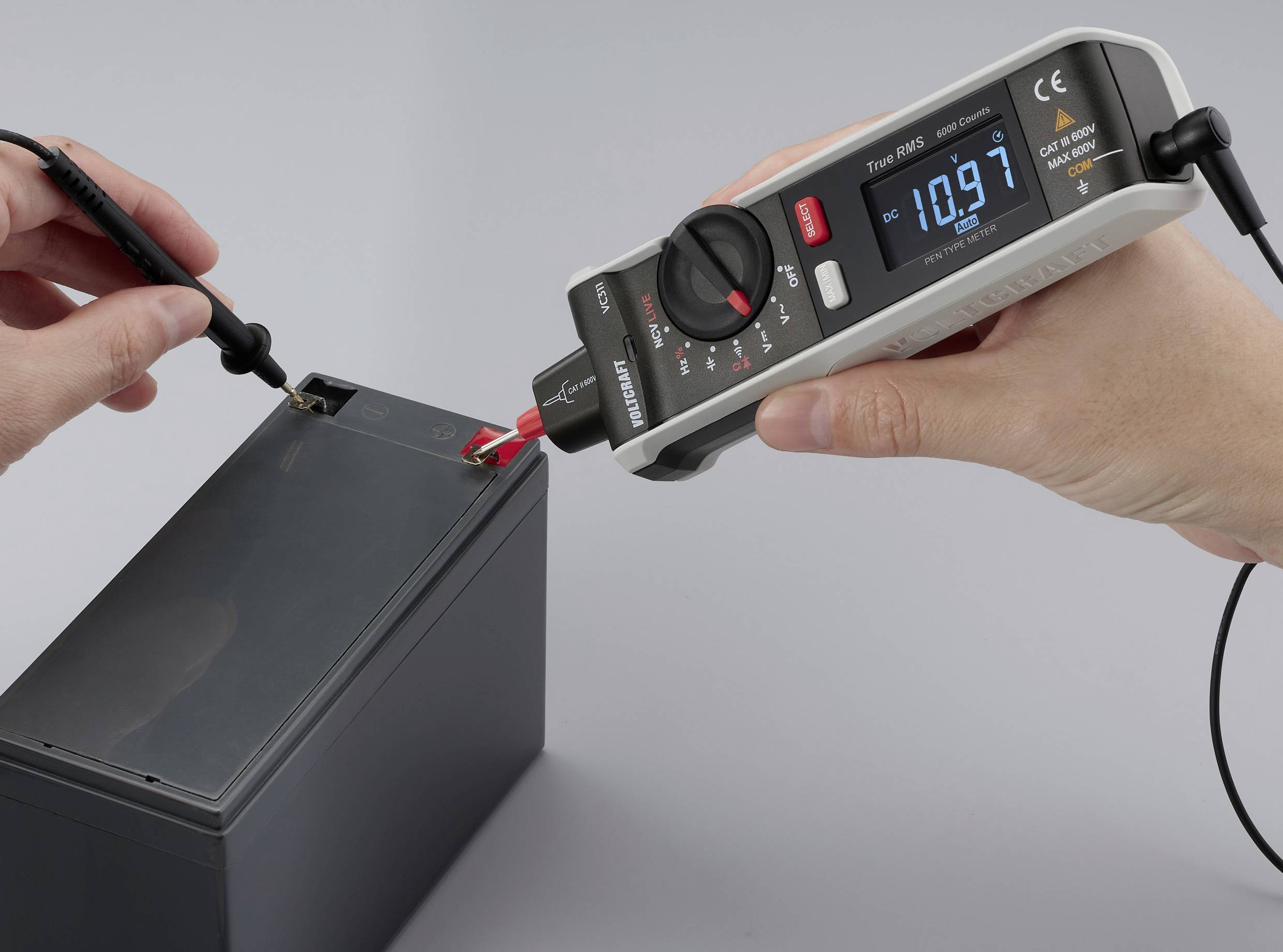 Ein Mensch verwendet ein digitales Multimeter, um die Spannung einer Batterie zu messen, wobei auf dem Display 10,97 Volt angezeigt werden.