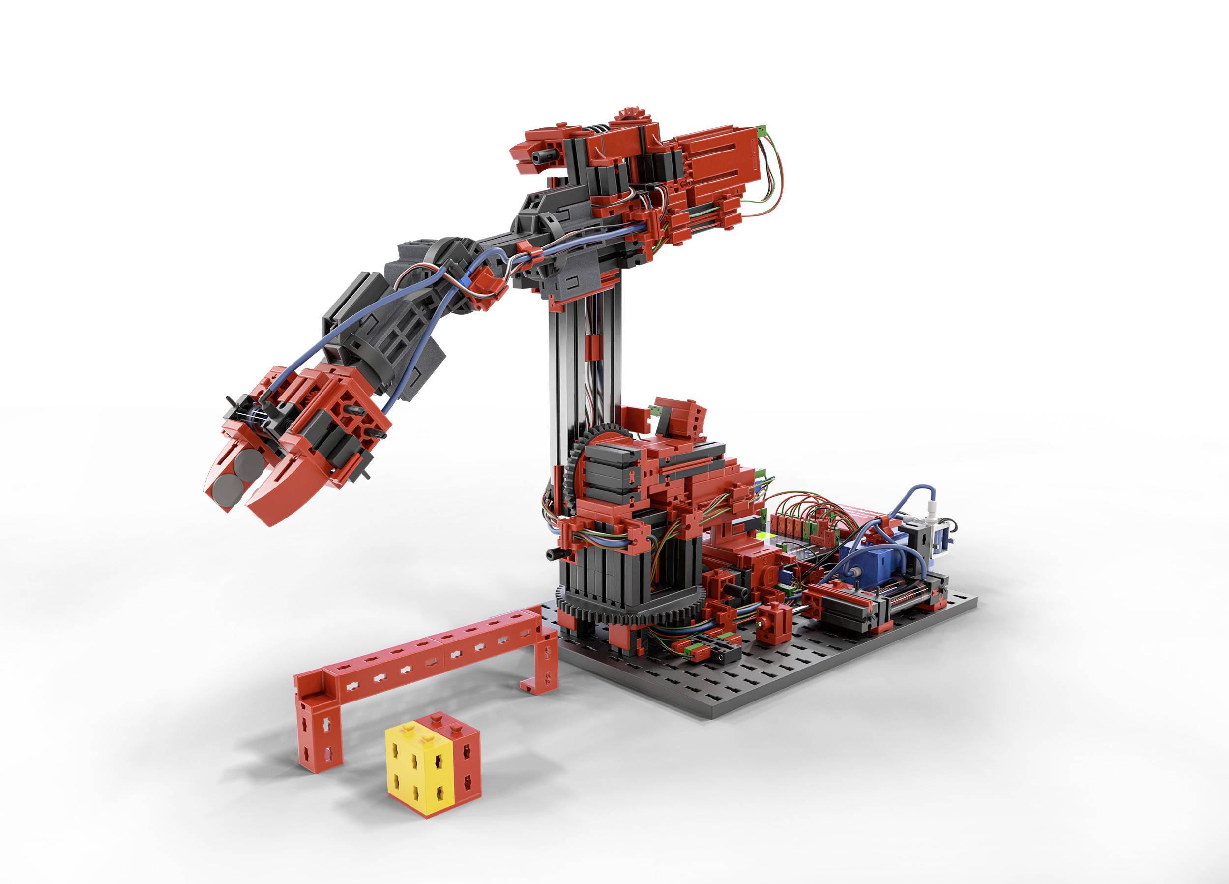 Ein roter Roboterarm aus Bausatzteilen hebt einen gelben Würfel, umgeben von weiteren Bauelementen auf einer schwarzen Basis.