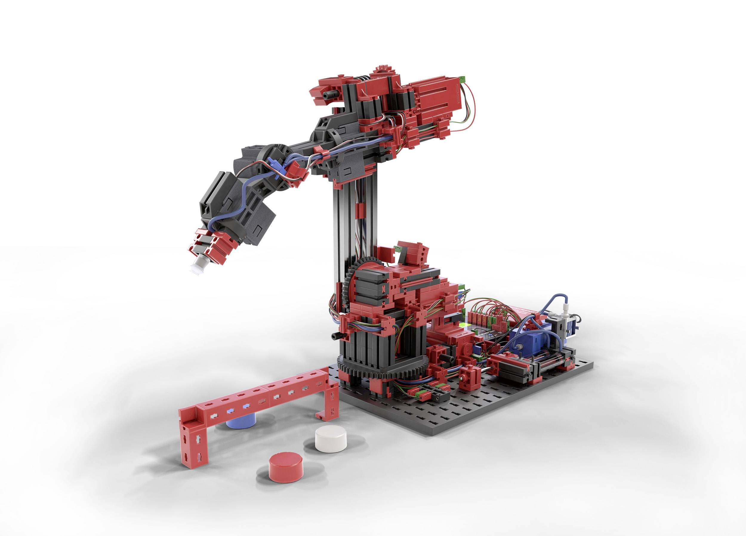 Ein roter Roboterarm aus Bauklötzen, der über einer Plattform steht. Darunter liegen bunte Blöcke auf einer weißen Oberfläche.