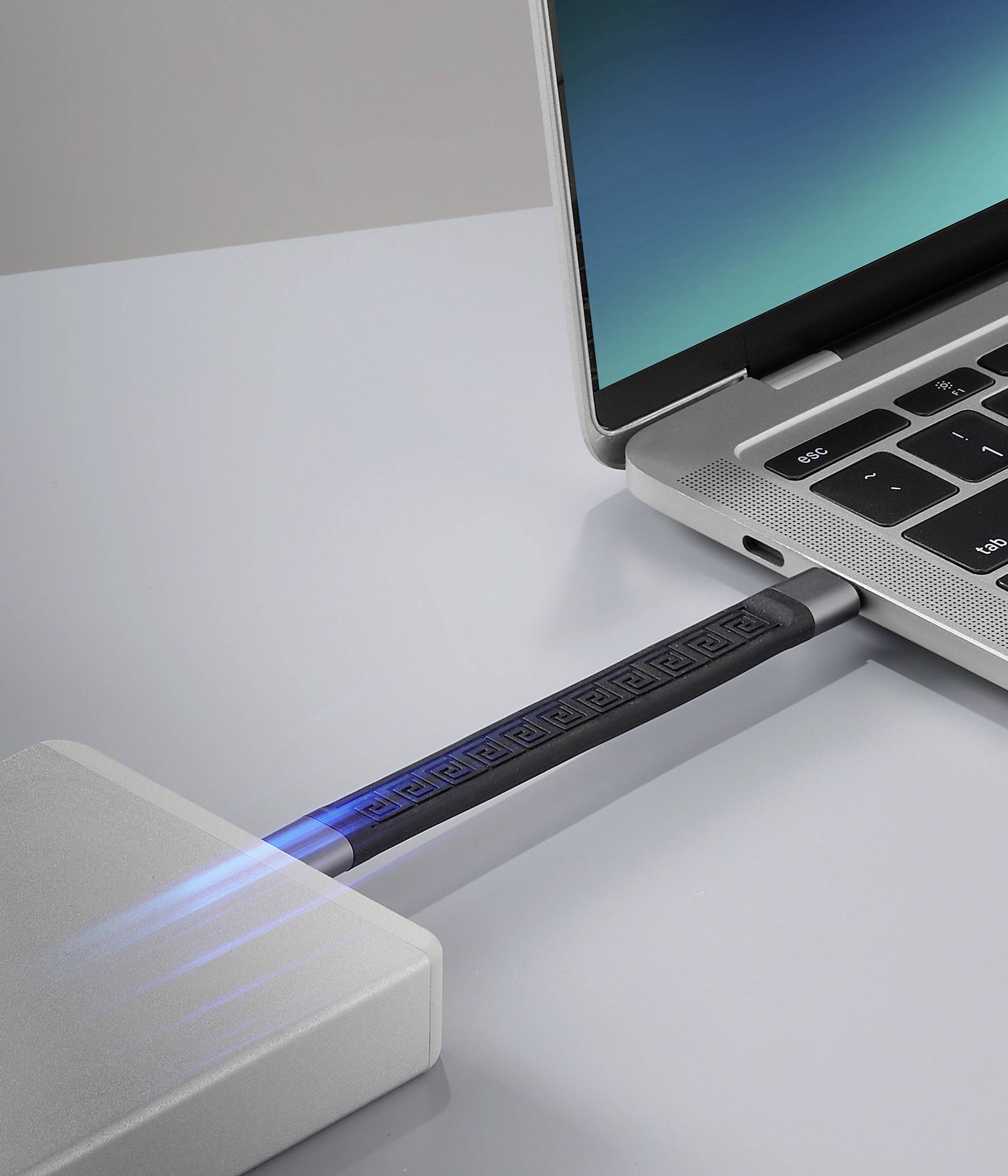 Laptop mit geöffneter Klappe auf einem Tisch, angeschlossen an ein externer Speichergerät durch ein leuchtendes USB-Kabel.