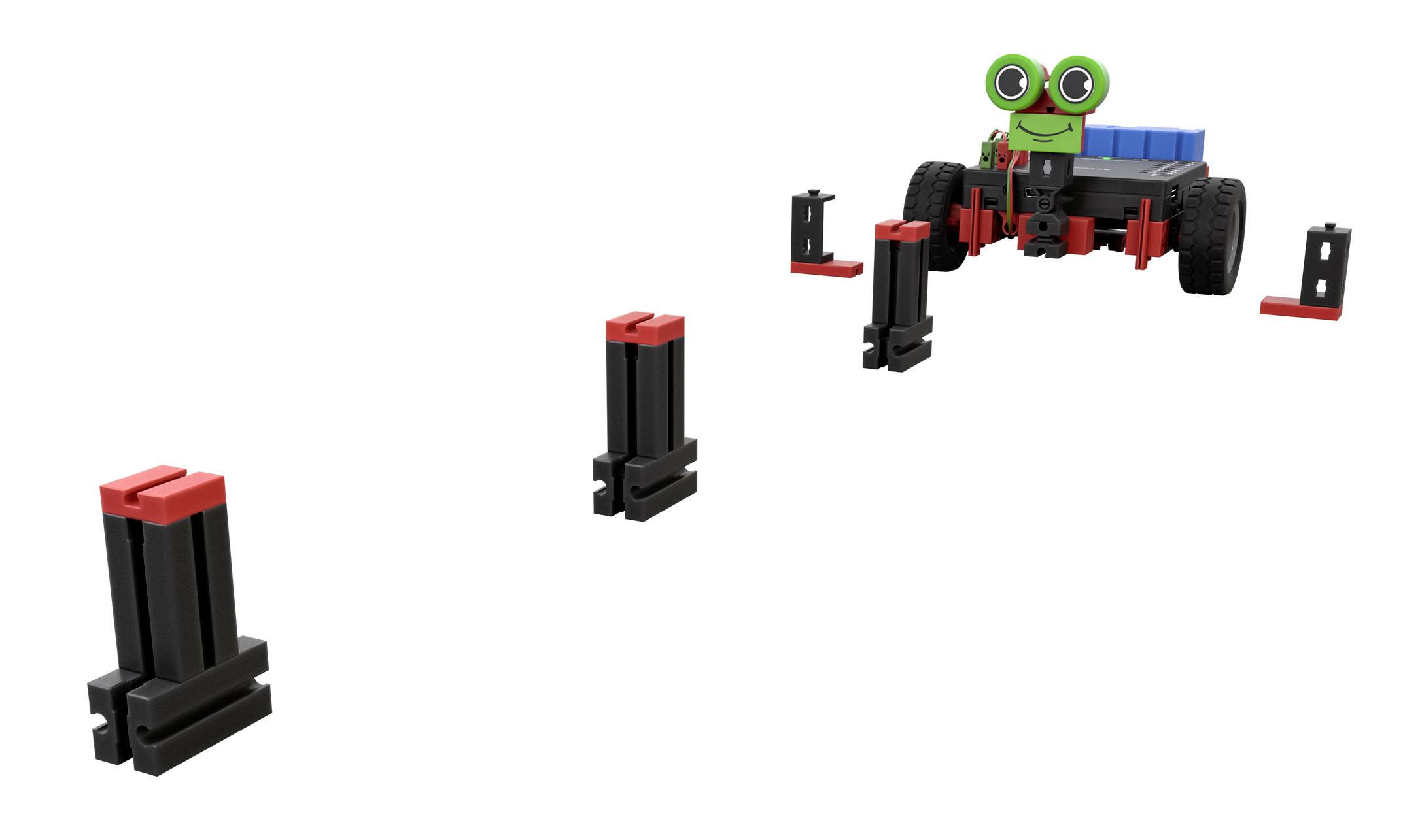 Ein kleines, roboterähnliches Fahrzeug mit grünem Gesicht fährt auf einer Strecke aus schwarzen und roten Blöcken.