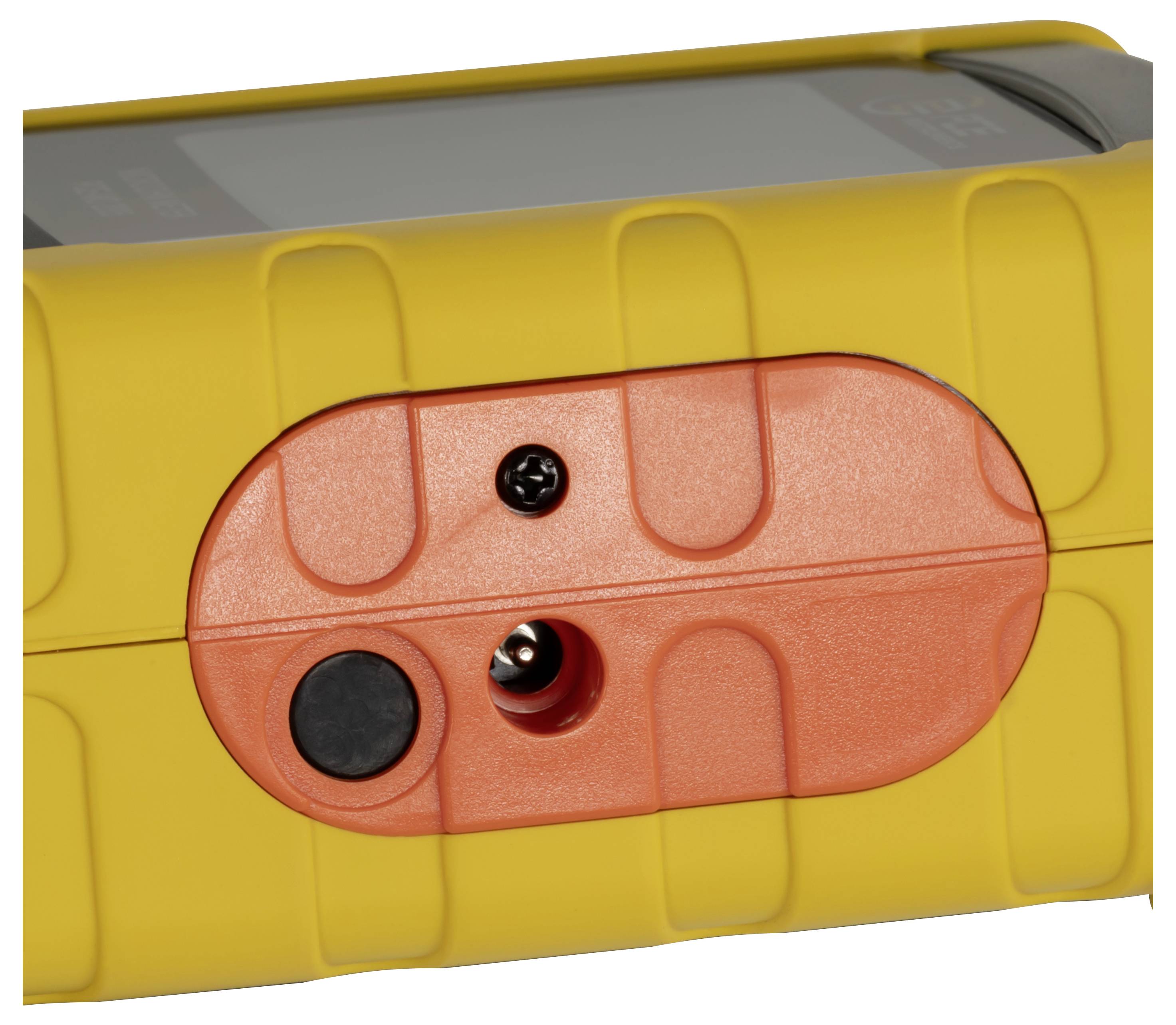 Nahaufnahme eines gelben Geräts mit einem orangefarbenen ovalen Bedienfeld, auf dem ein schwarzer Knopf und eine zentrale Schraube oder ein Anschlussport zu sehen sind.
