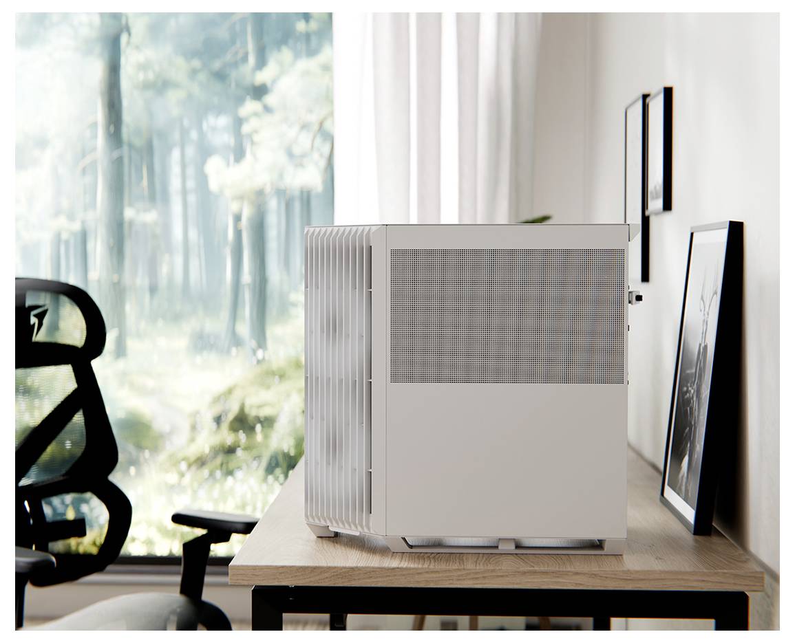 Ein kleines Computergehäuse steht auf einem Holzschreibtisch neben einem schwarzen Bürostuhl, wobei ein großes Fenster einen Blick auf einen Waldausschnitt freigibt.