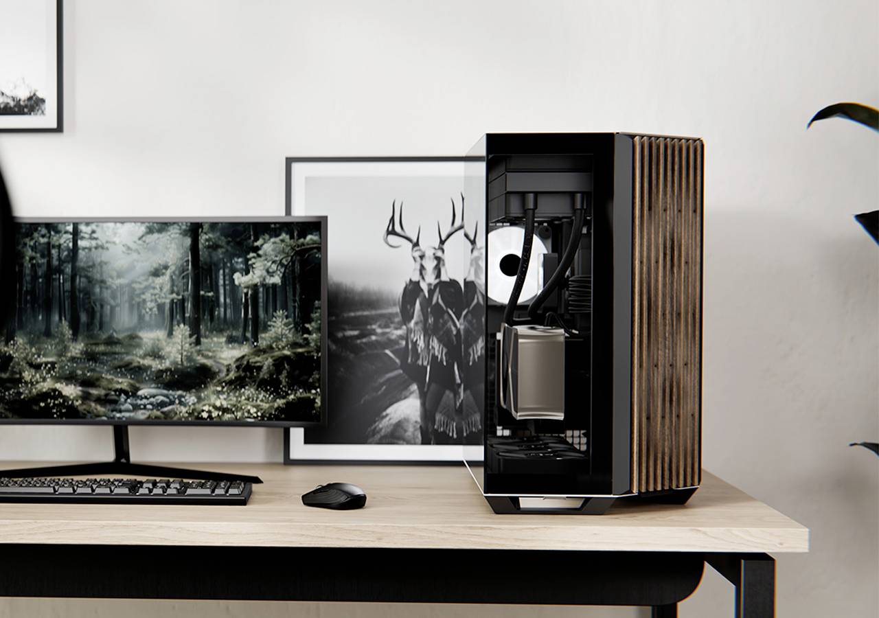 Ein minimalistischer Arbeitsplatz mit einem Computer, auf dessen Monitor eine Waldszene zu sehen ist, einem kompakten schwarzen Desktop-Tower mit Holzelementen und einer Maus auf einem Holzschreibtisch.