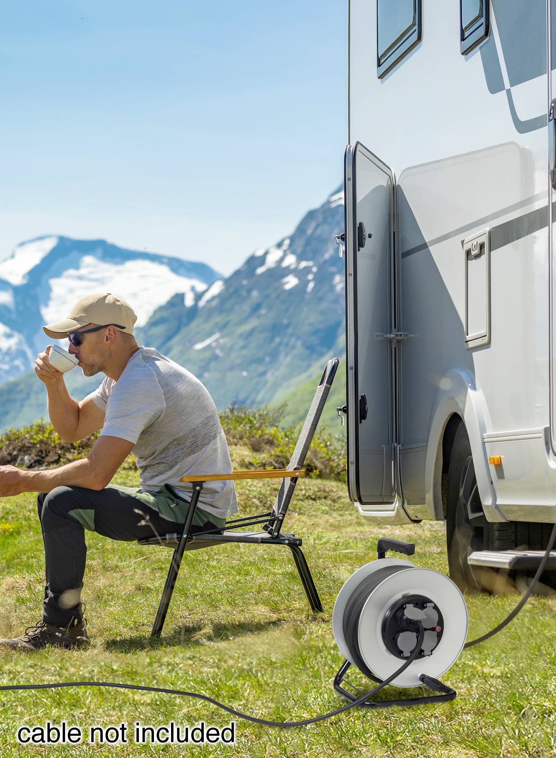 Ein Mann sitzt auf einem Stuhl neben einem Wohnmobil in einer Berglandschaft und trinkt aus einer Tasse. Ein Kabel liegt daneben.