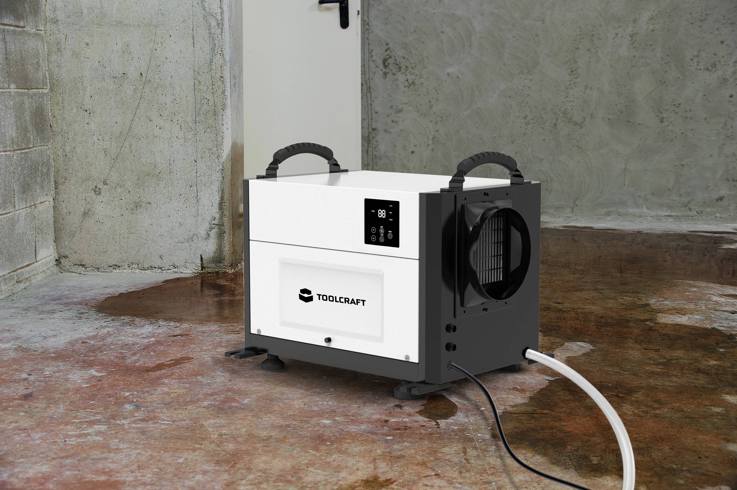 Luftentfeuchter im Keller auf Betonboden in Betrieb, mit Kabel angeschlossen. Wände sind grob verputzt, Boden ist teils feucht.