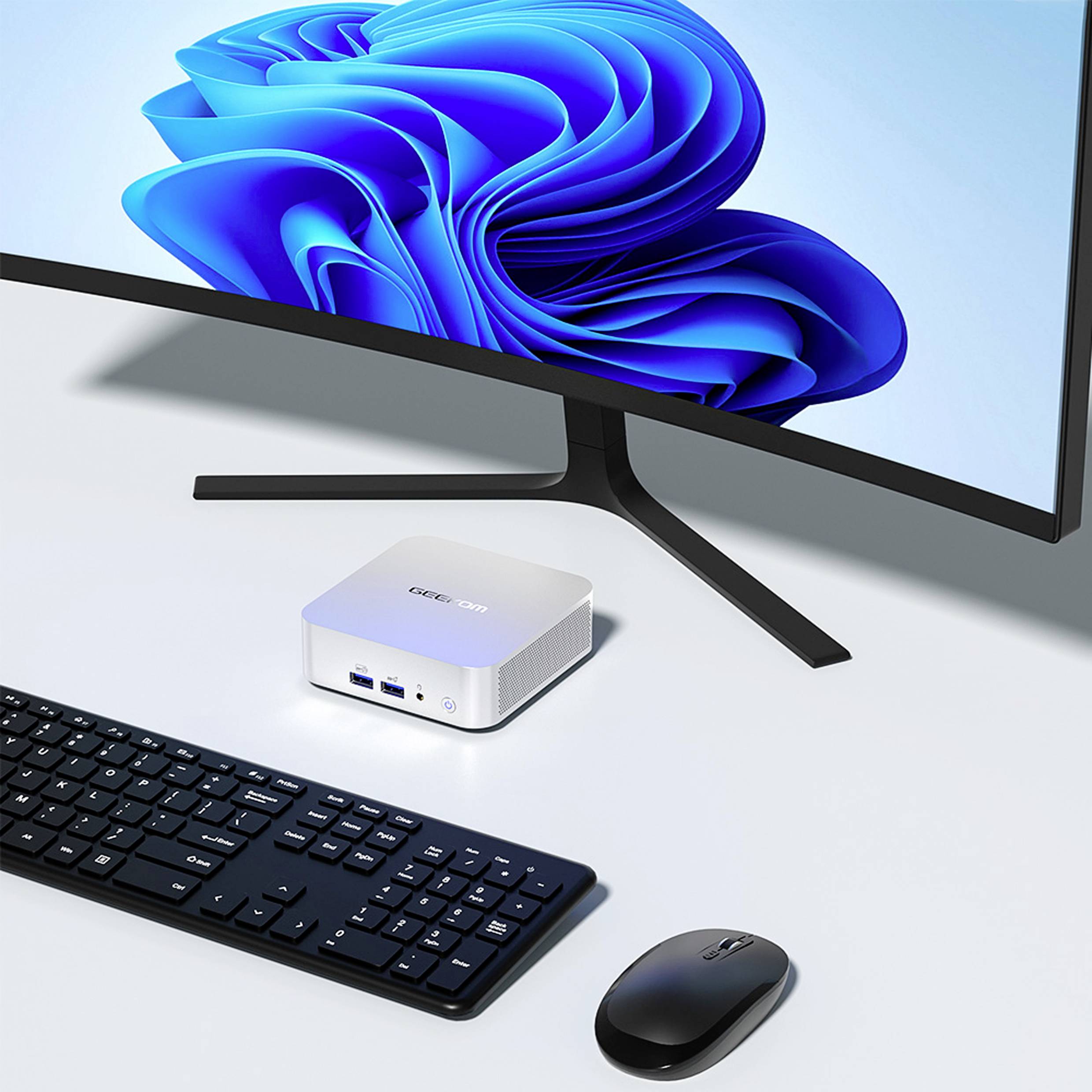 Ein Desktop-Setup mit einem Monitor, einer kompakten Computerbox, einer Tastatur und einer Maus. Der Monitor zeigt eine blaue Spiralgrafik.