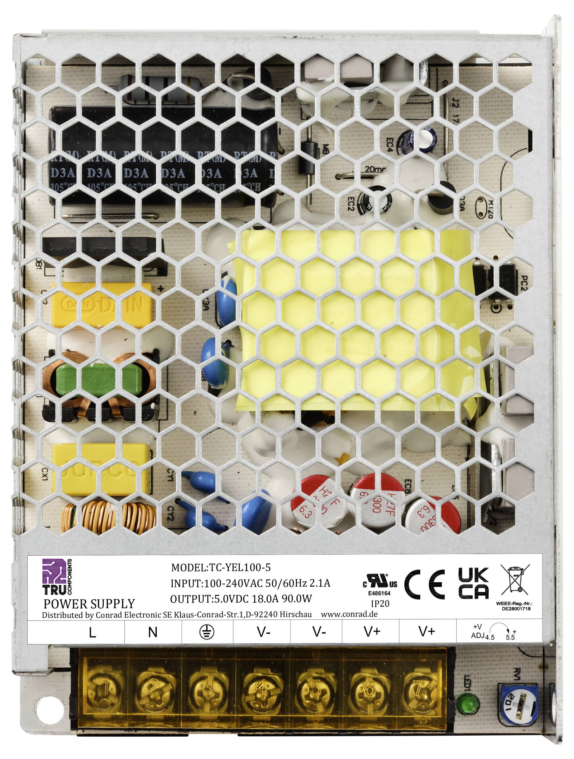 Stromversorgungseinheit TRU TC-YEL100.5 mit Modell- und Spannungsspezifikationen. Sechseckiges Metallgitter zeigt interne Komponenten.