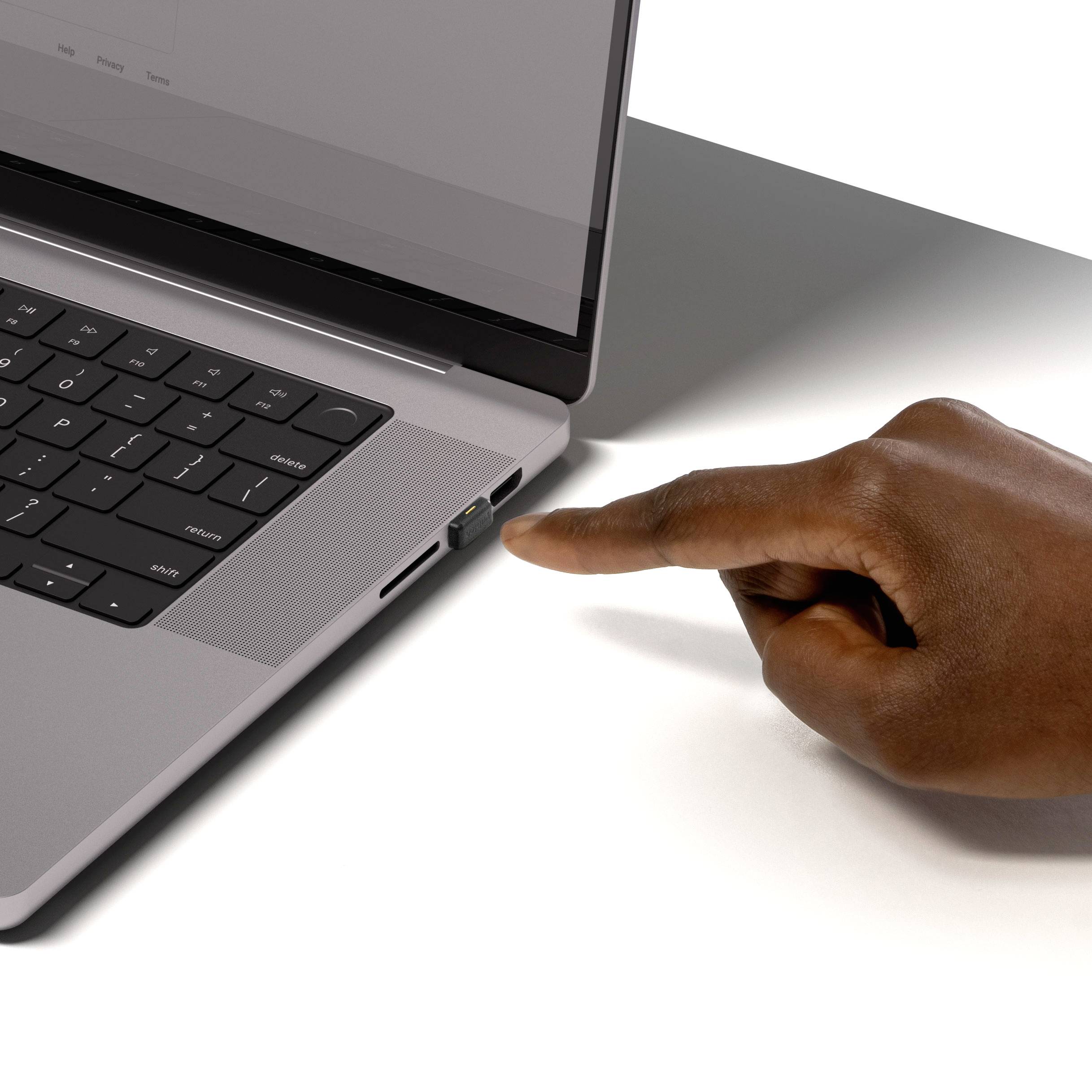 Eine Person zeigt auf den USB-Anschluss eines geöffneten Laptops mit Tastaturansicht.