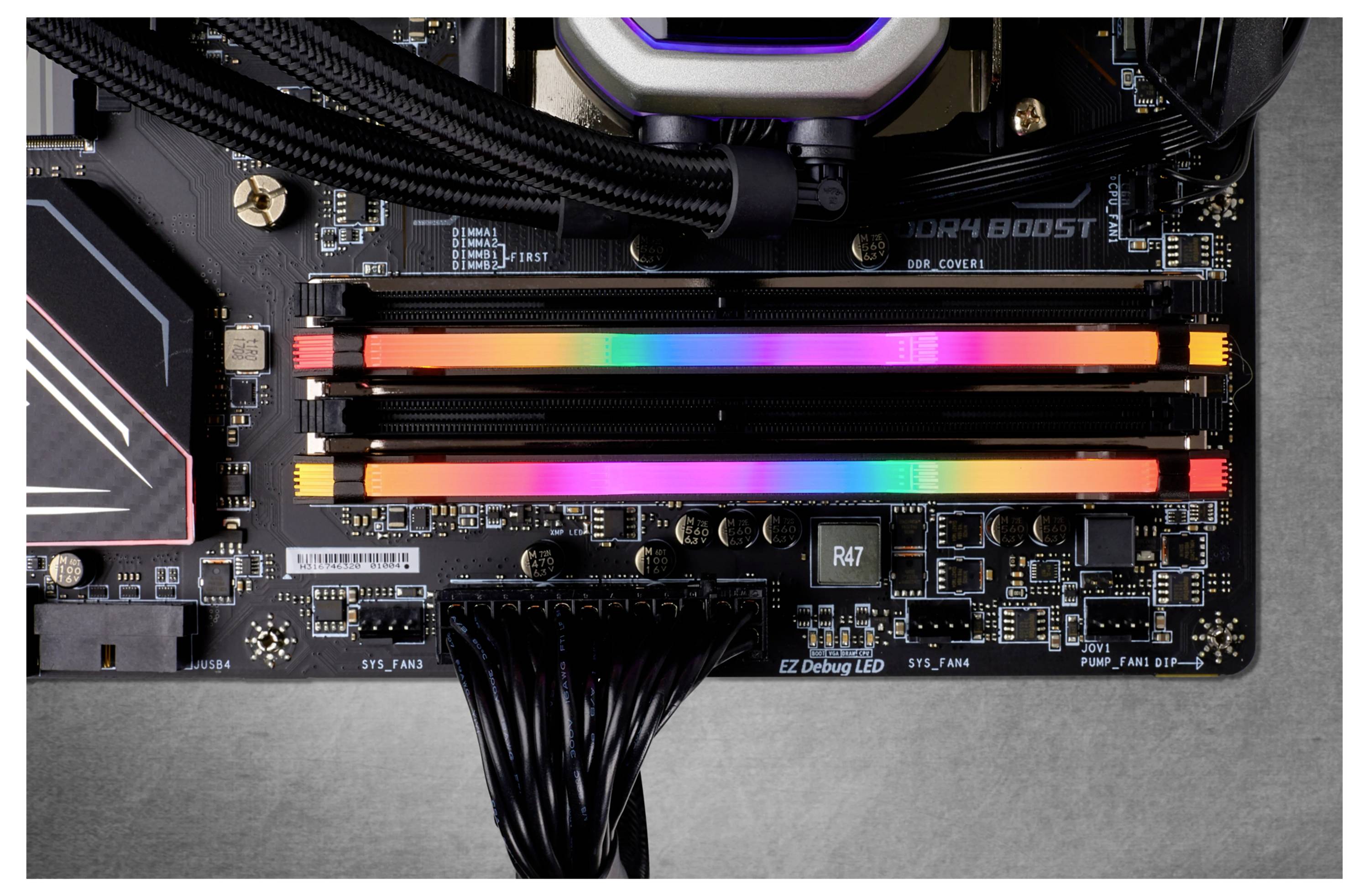 Ein Computer-Mainboard mit zwei RAM-Riegeln, die in Regenbogenfarben leuchten, zeigt eine RGB-Beleuchtung.